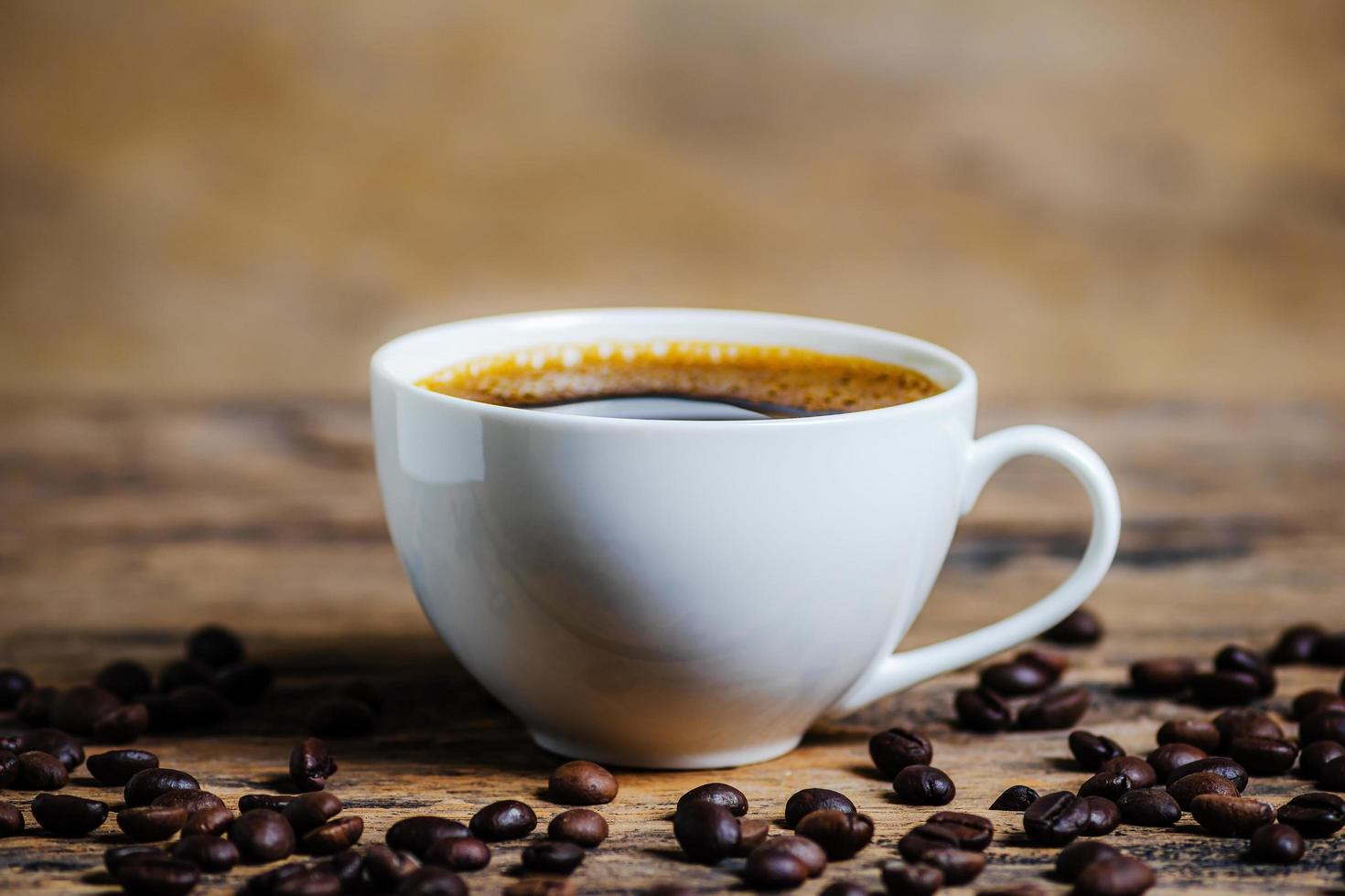 una taza de café con granos de café sobre fondo de madera foto