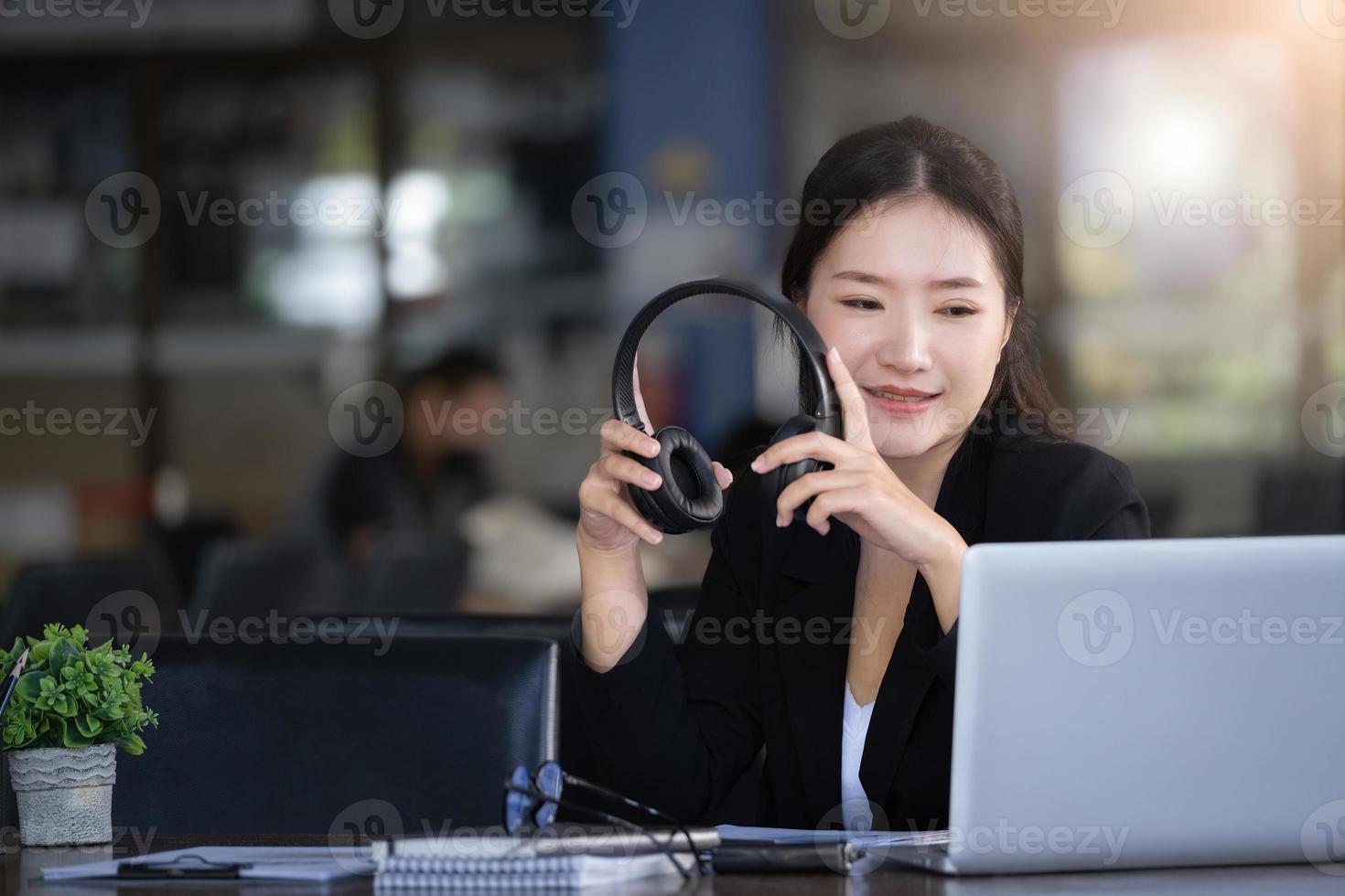 concepto de tomarse un descanso del trabajo, una contadora o una empleada de una empresa o una propietaria de una empresa está usando auriculares para escuchar música para aliviar el estrés y la fatiga del trabajo. foto