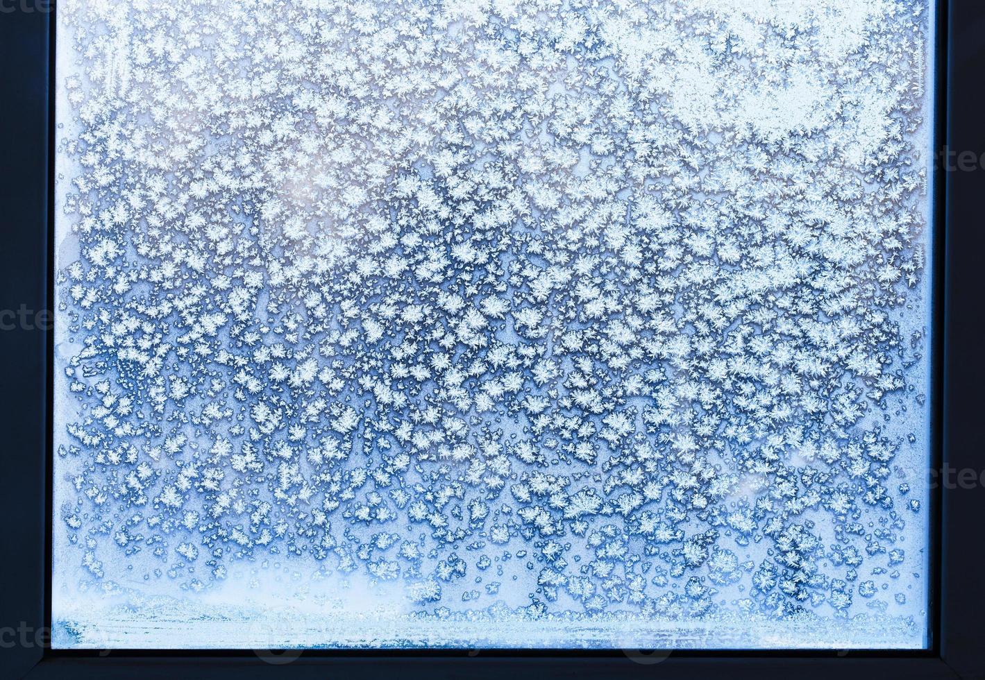 ventana de casa con copos de nieve y escarcha en invierno foto