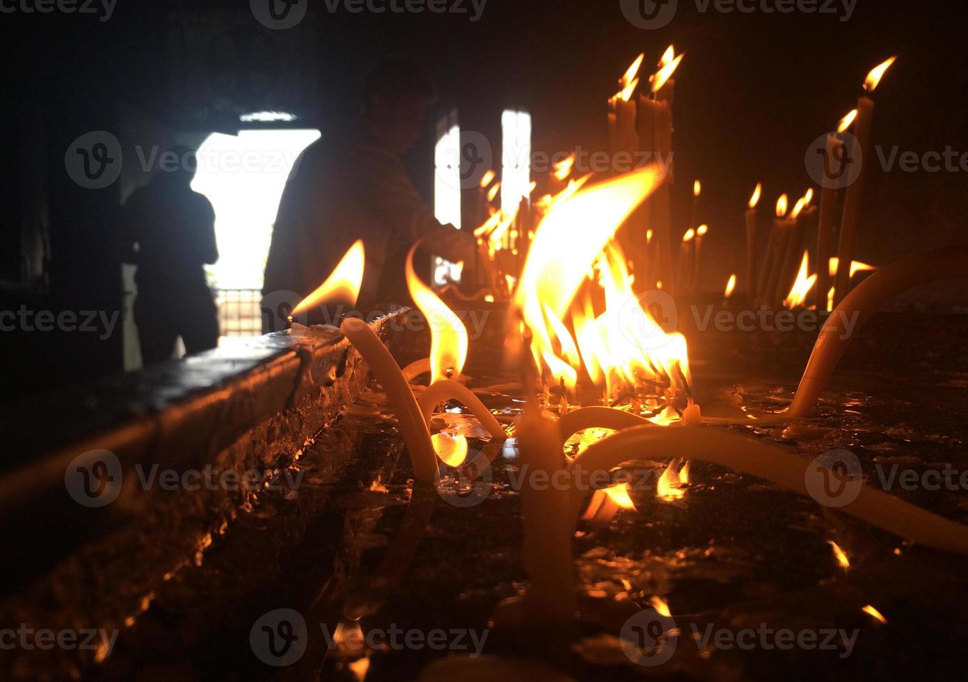 Many candles burning in a dark room photo