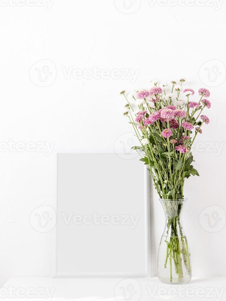 White frame mockup with chrysanthemum flowers in a vase on a white table photo