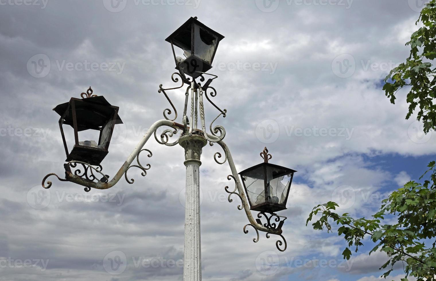 viejas luces de la calle rotas contra un cielo nublado foto