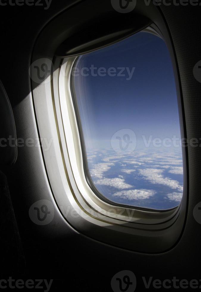 The sun shines through a plane window at cruising altitude photo