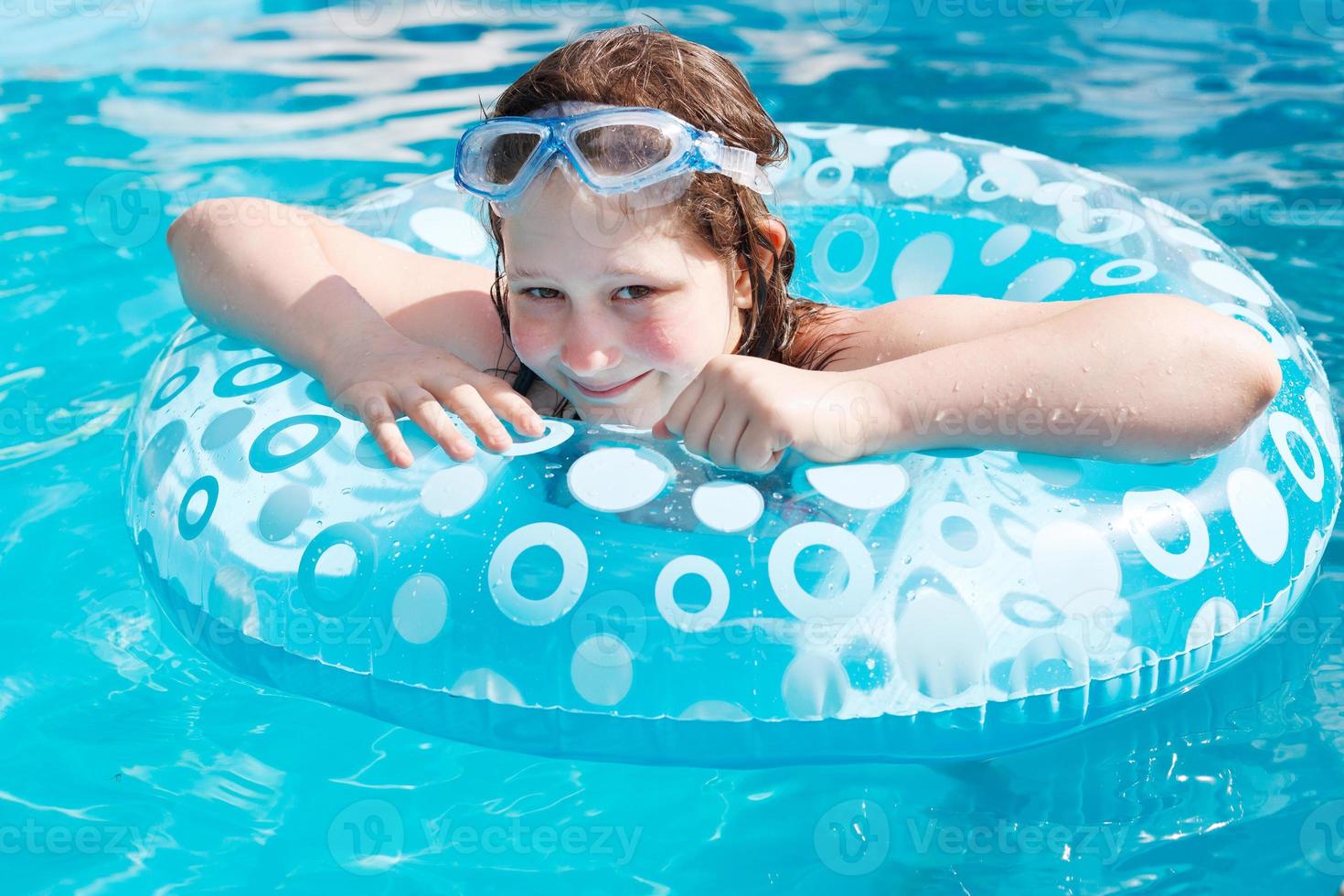girl on inflatable circle in blue open-air pool photo