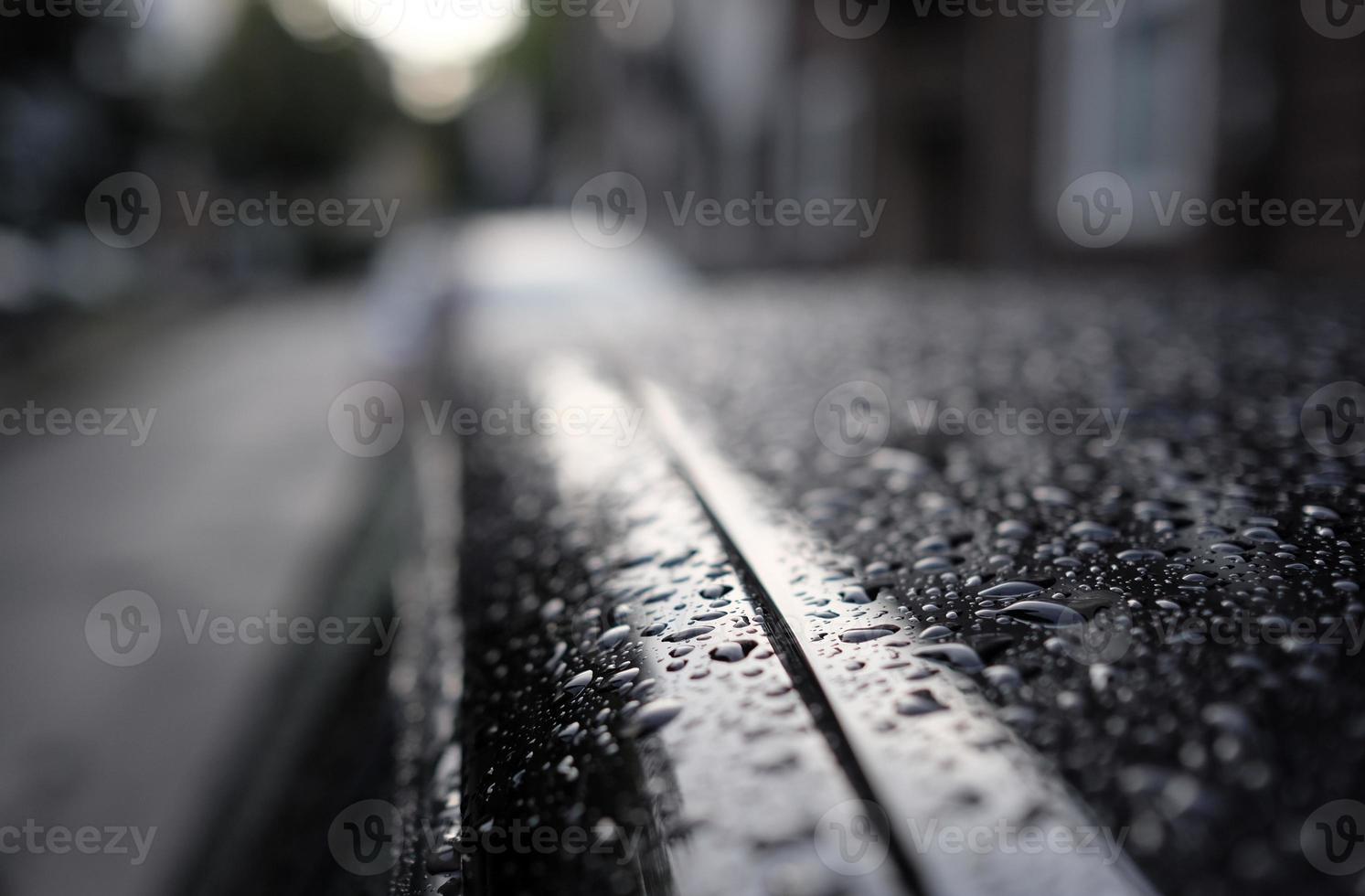 Selective focus on rain drops on top of a black car photo