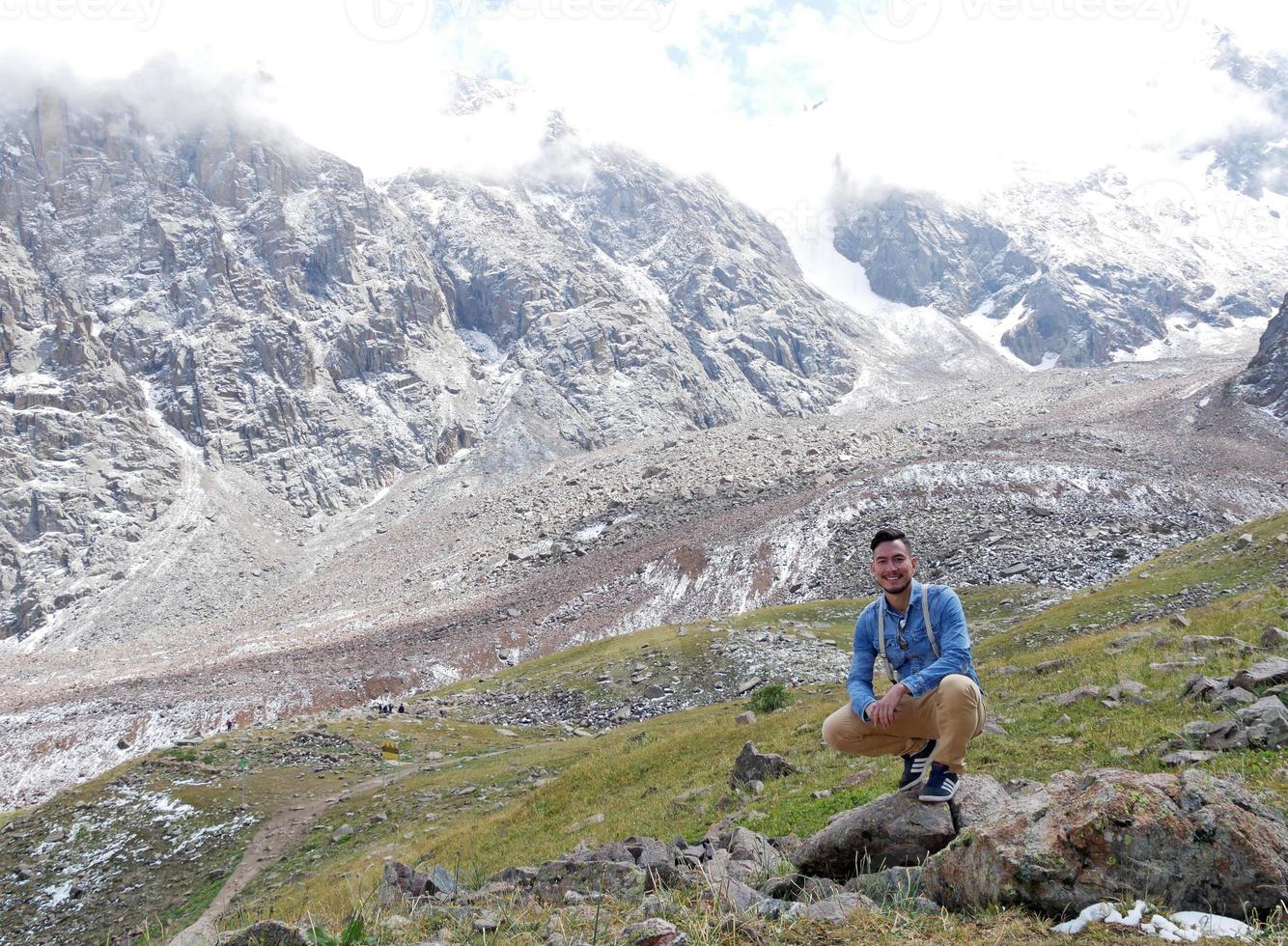 Man crouching in front of a mountain range in Kazakhstan photo