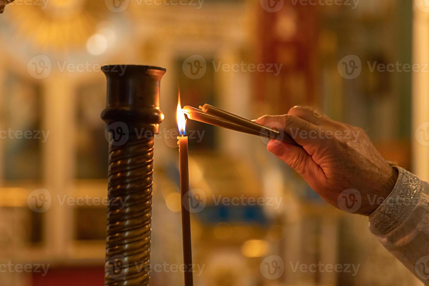 Orthodox Church. Christianity. Hand of priest lighting burning candles in traditional Orthodox Church on Easter Eve or Christmas. Religion faith pray symbol. photo