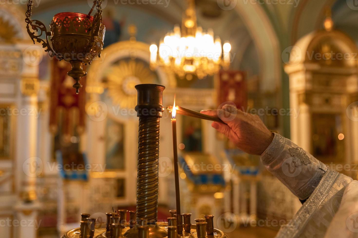 Orthodox Church. Christianity. Hand of priest lighting burning candles in traditional Orthodox Church on Easter Eve or Christmas. Religion faith pray symbol. photo