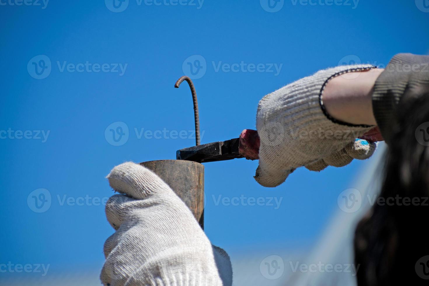 The technician keeps bending the metal rod in his hand with pliers. Pliers in the hands of men. Electrician. photo