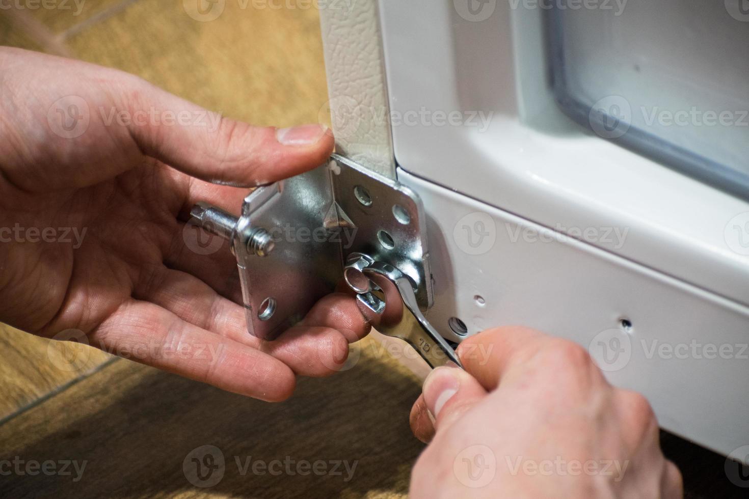 Man holds a wrench in his hand. the man is repairing the door. Hand tool. photo