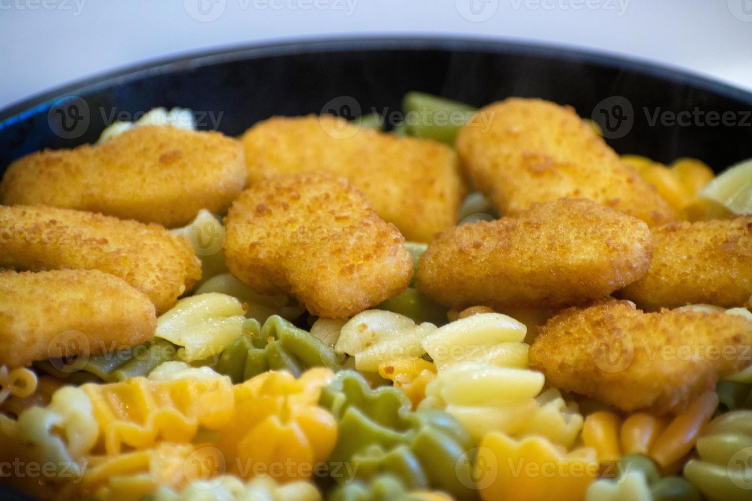 Pasta with chicken nuggets in a frying pan. Fried Chicken Nuggets. Tasty, crispy chicken nuggets. Children's menu. photo