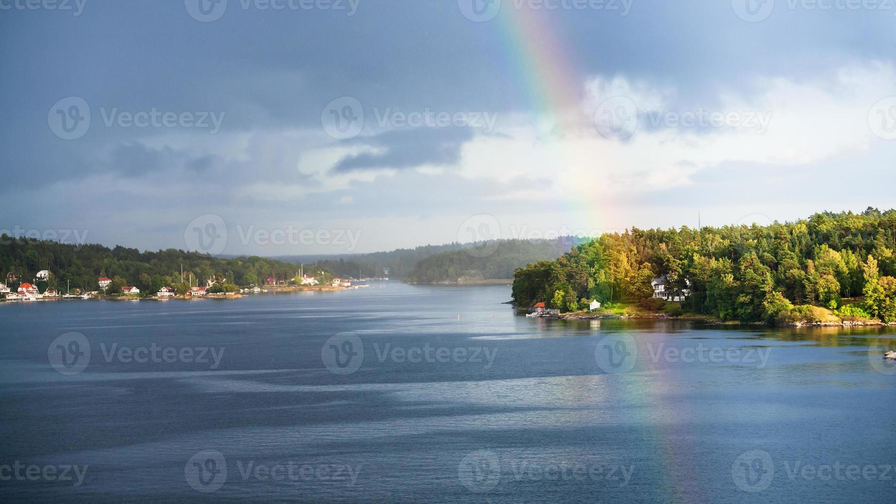 green coast with settlements and rainbow photo