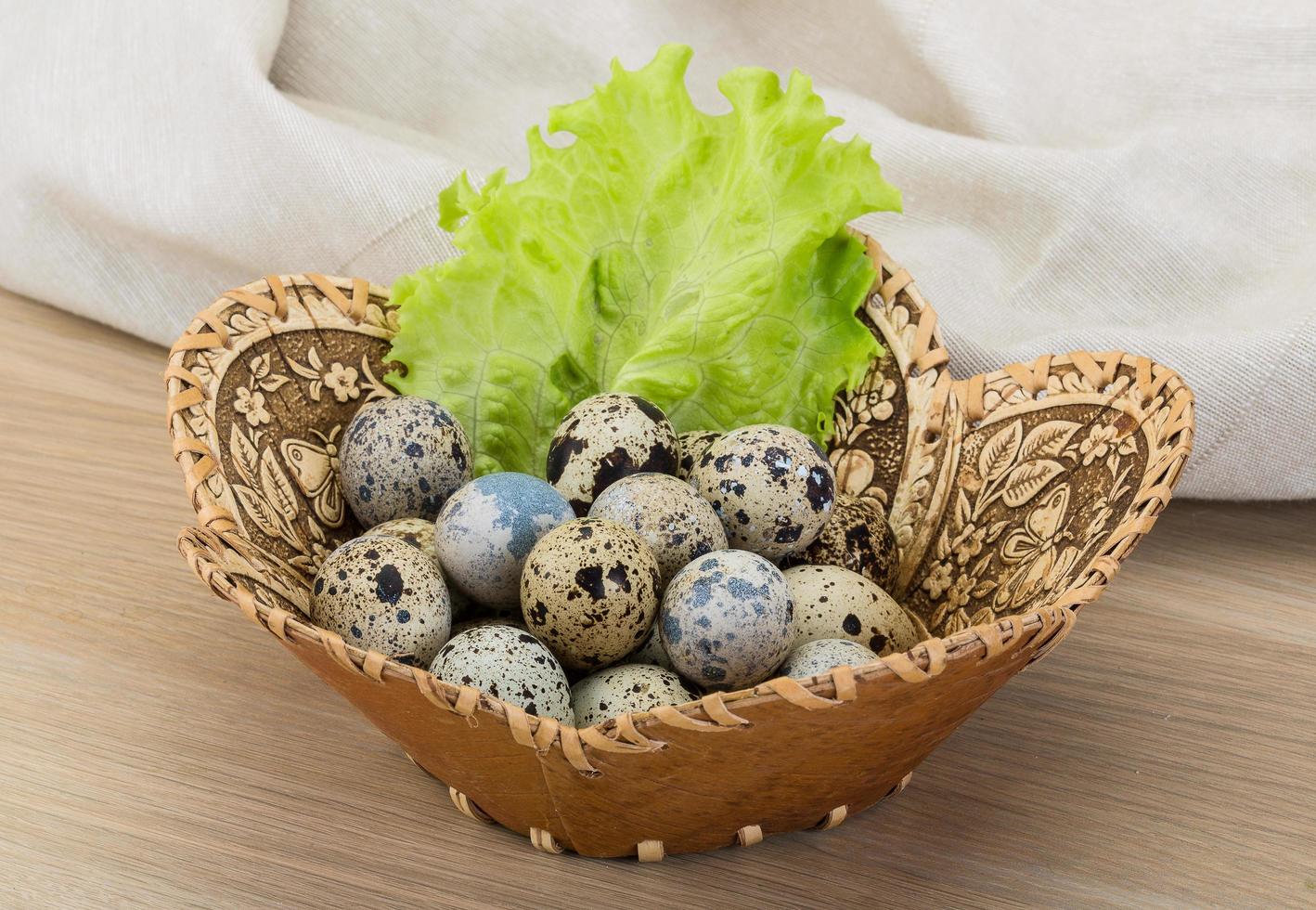 Quail eggs in a basket on wooden background photo