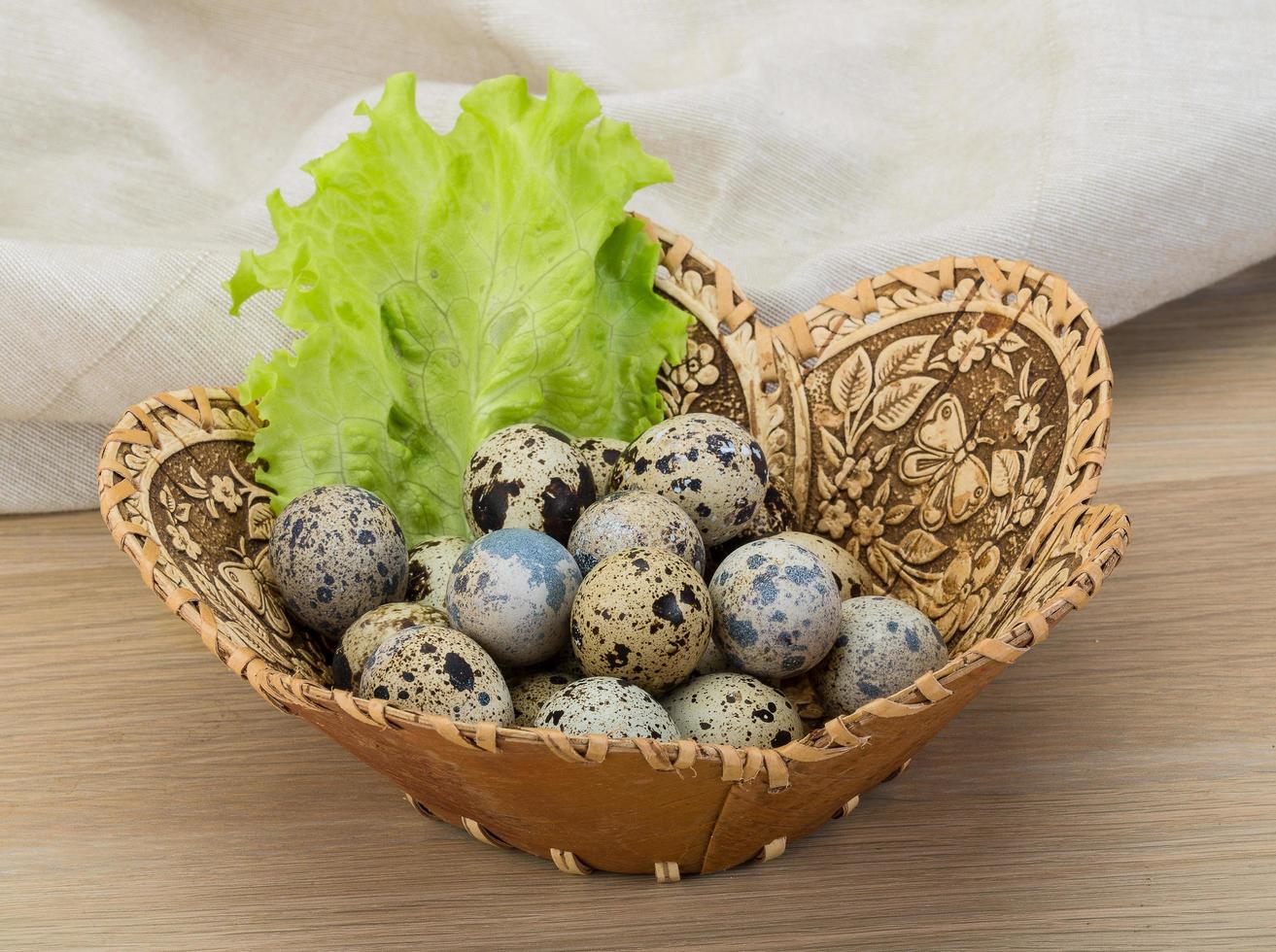 Quail eggs in a basket on wooden background photo