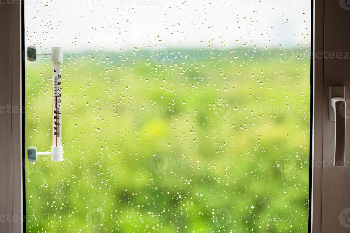 home window with rain drops and thermometer photo