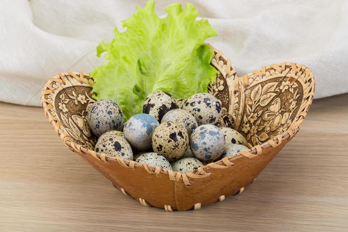 Quail eggs in a basket on wooden background photo