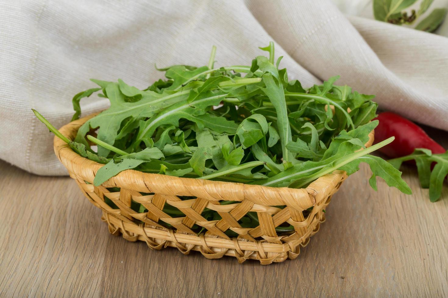 Ruccola in a basket on wooden background photo