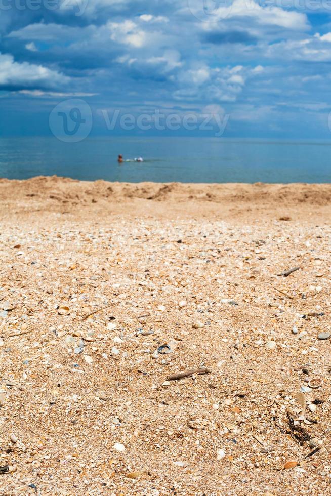 sand and shelly beach close up and dark blue sea photo