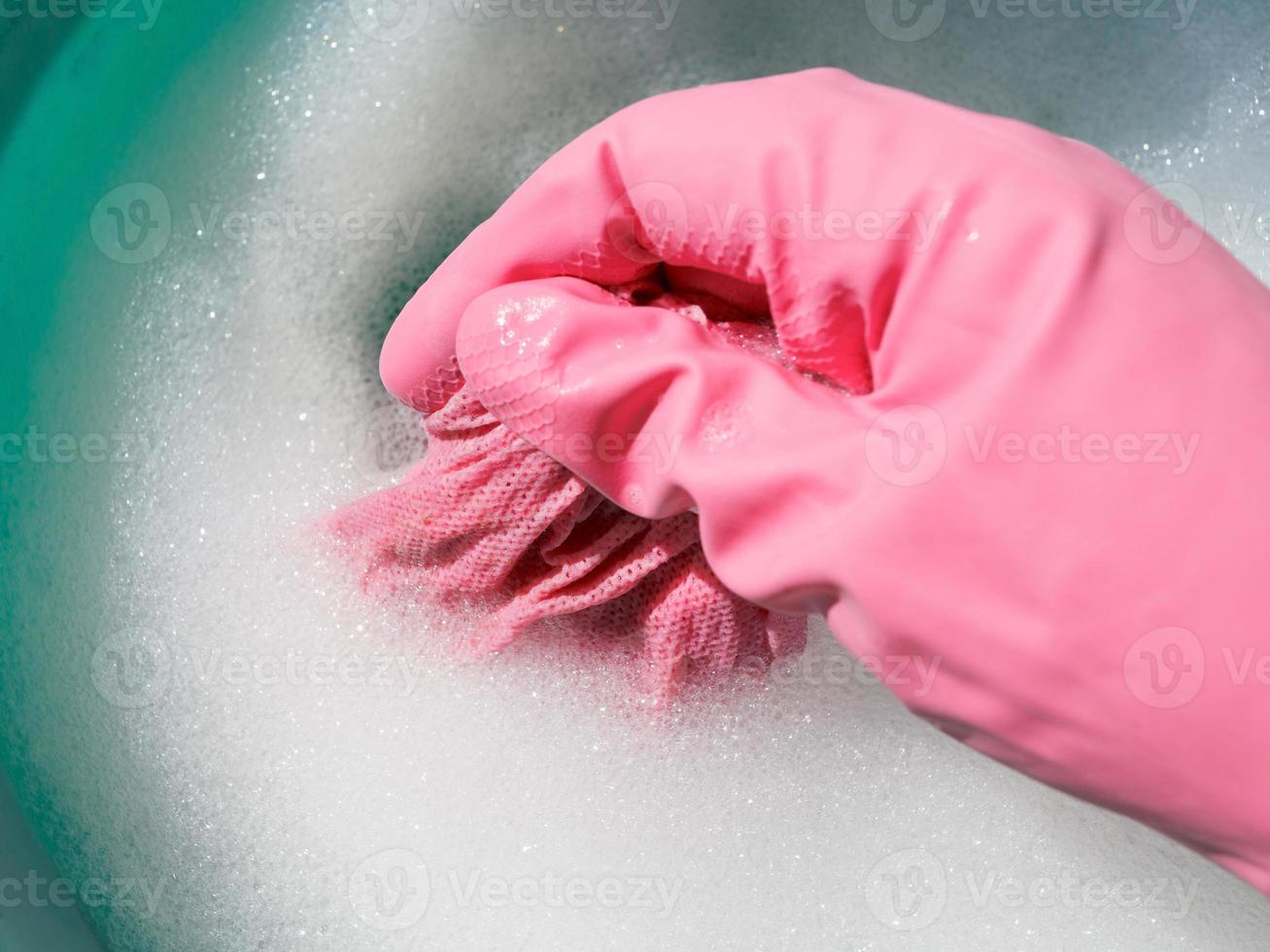 hand in pink rubber glove rinsing wet cloth photo