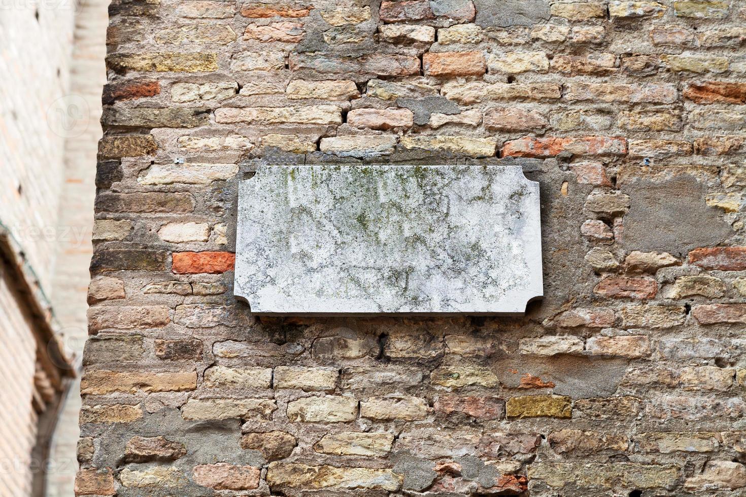 marble street sign on old brick wall photo