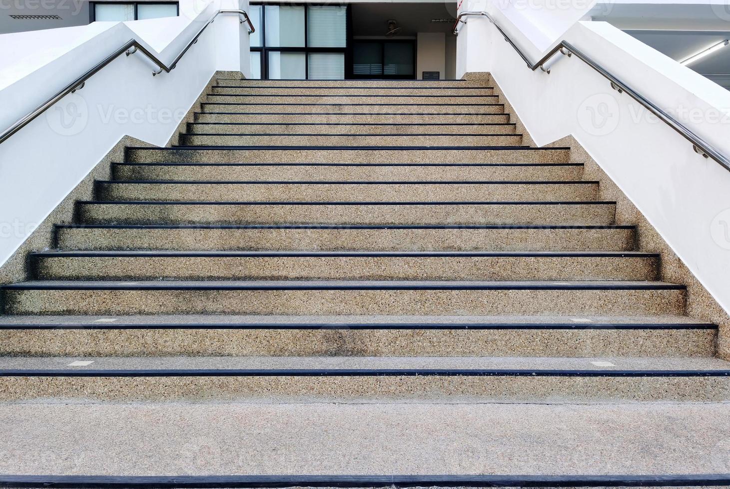 las escaleras de cemento en el camino hacia arriba y hacia abajo del edificio tienen manijas de acero en los lados izquierdo y derecho para evitar que las personas se caigan accidentes foto