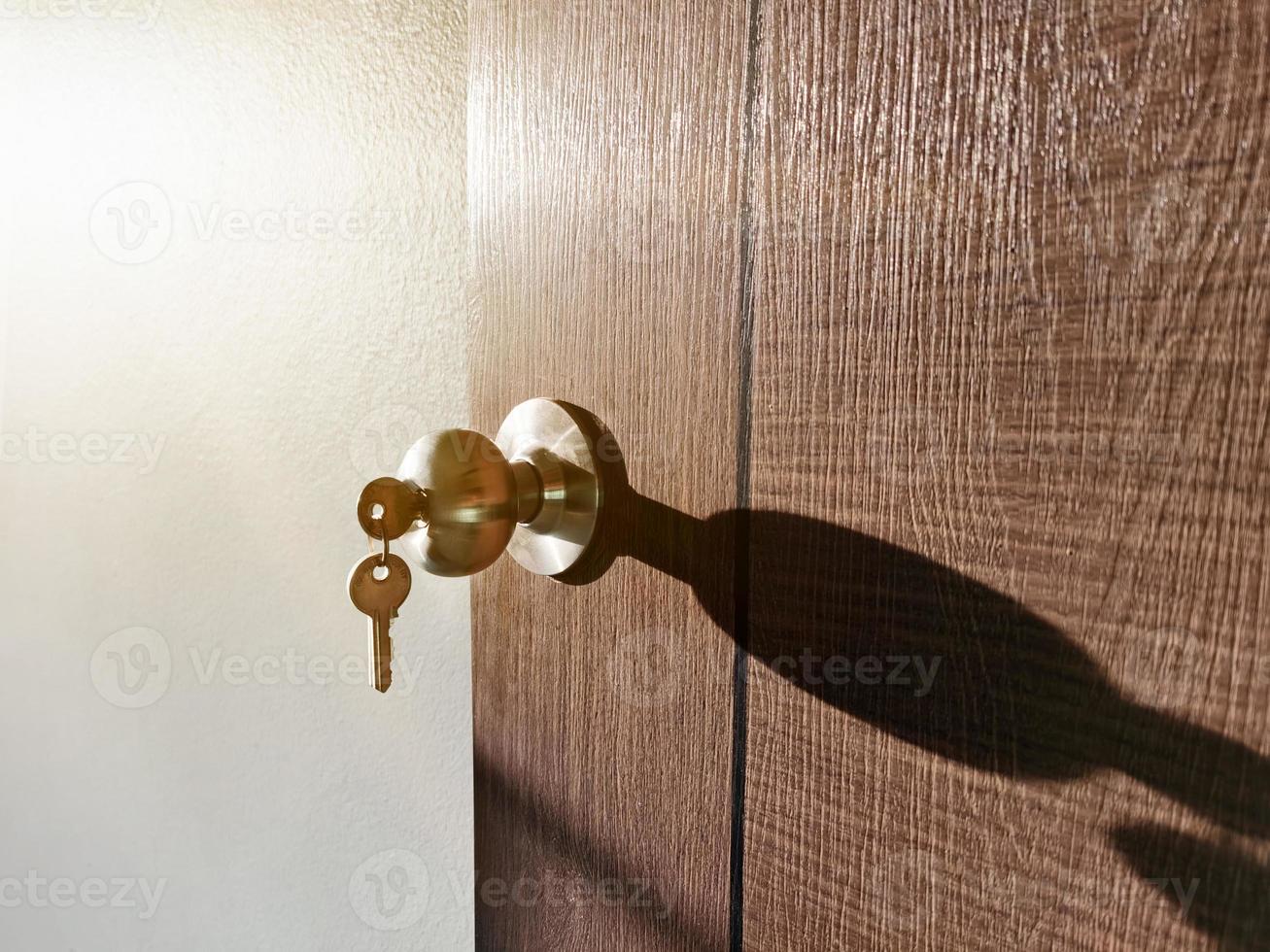 llave de la casa con el llavero de la casa en el ojo de la cerradura en la puerta de madera foto