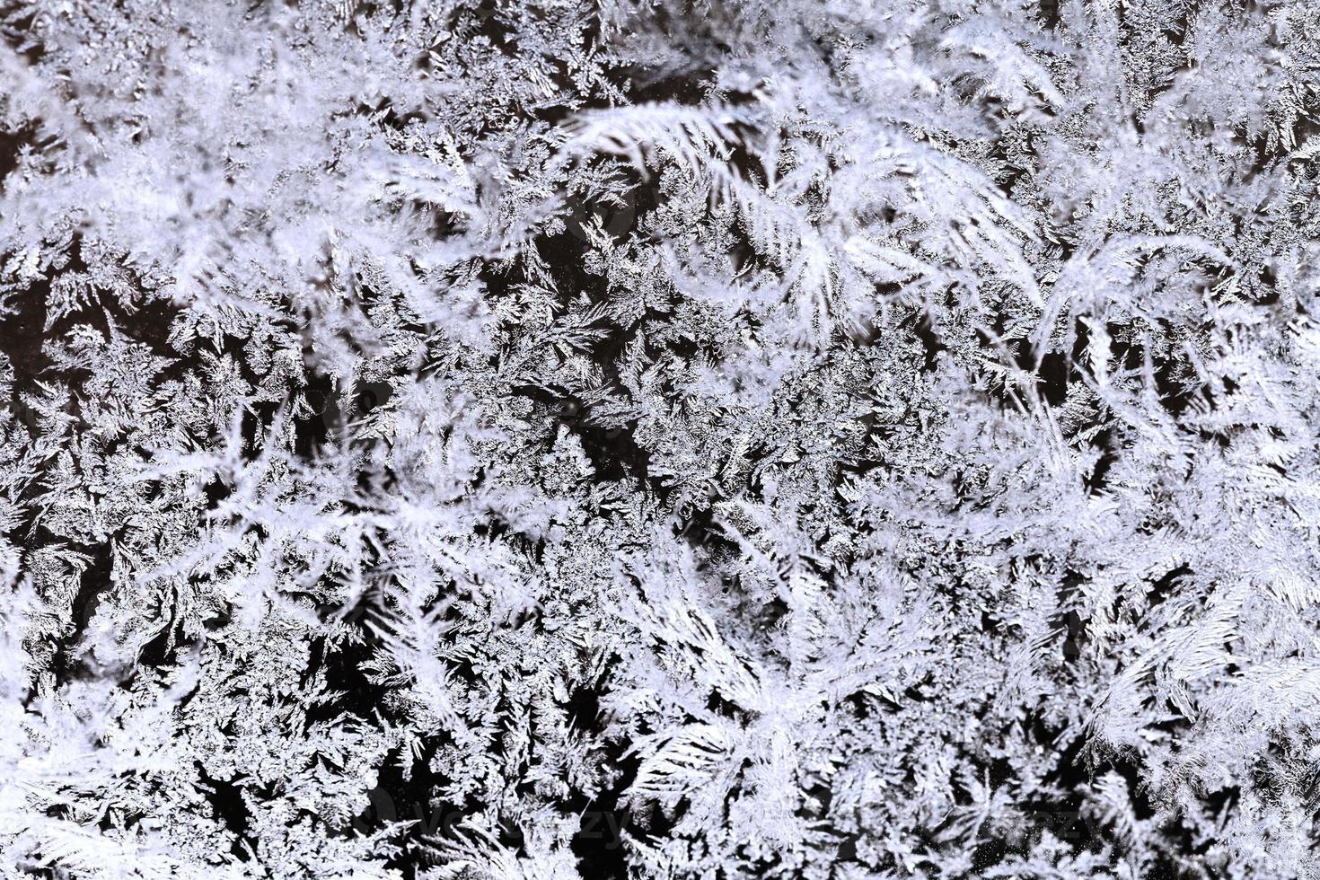 snowflakes and frost pattern on glass close up photo