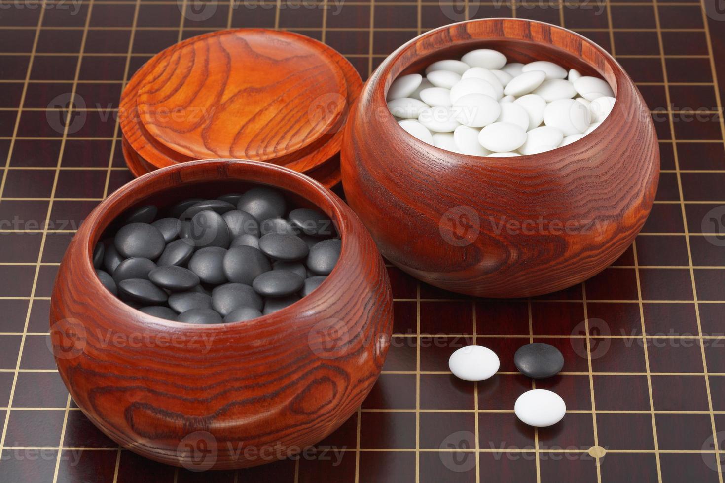 go game stones and wooden bowls on wood board photo