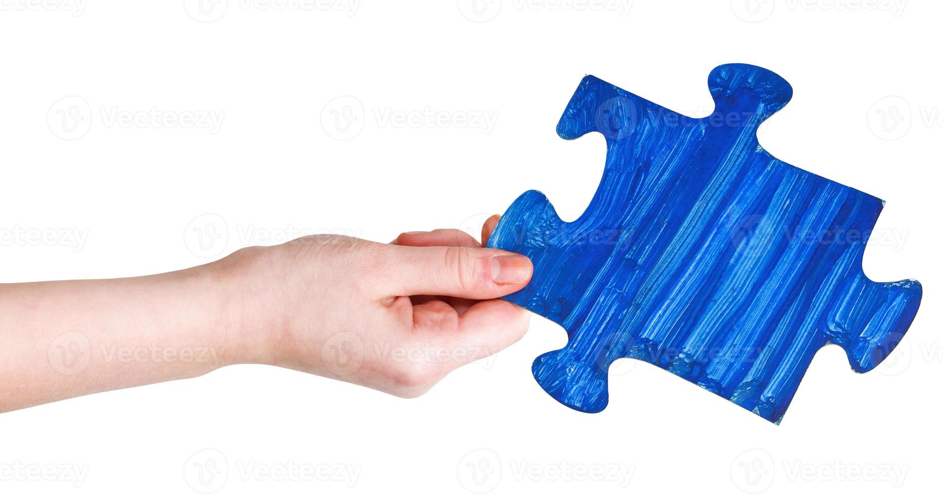 female hand with painted blue puzzle piece photo