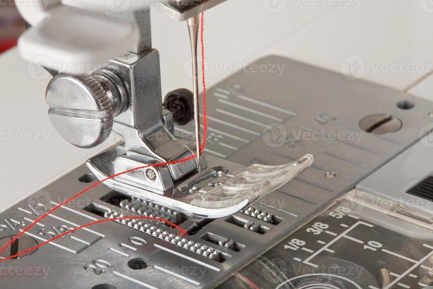 thread in needle of sewing machine closeup photo