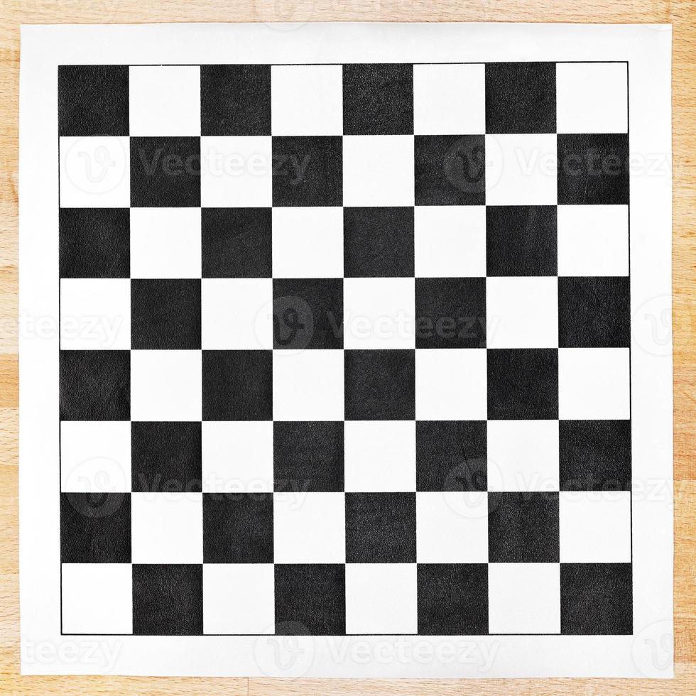 tablero de ajedrez de vinilo blanco y negro sobre mesa de madera foto