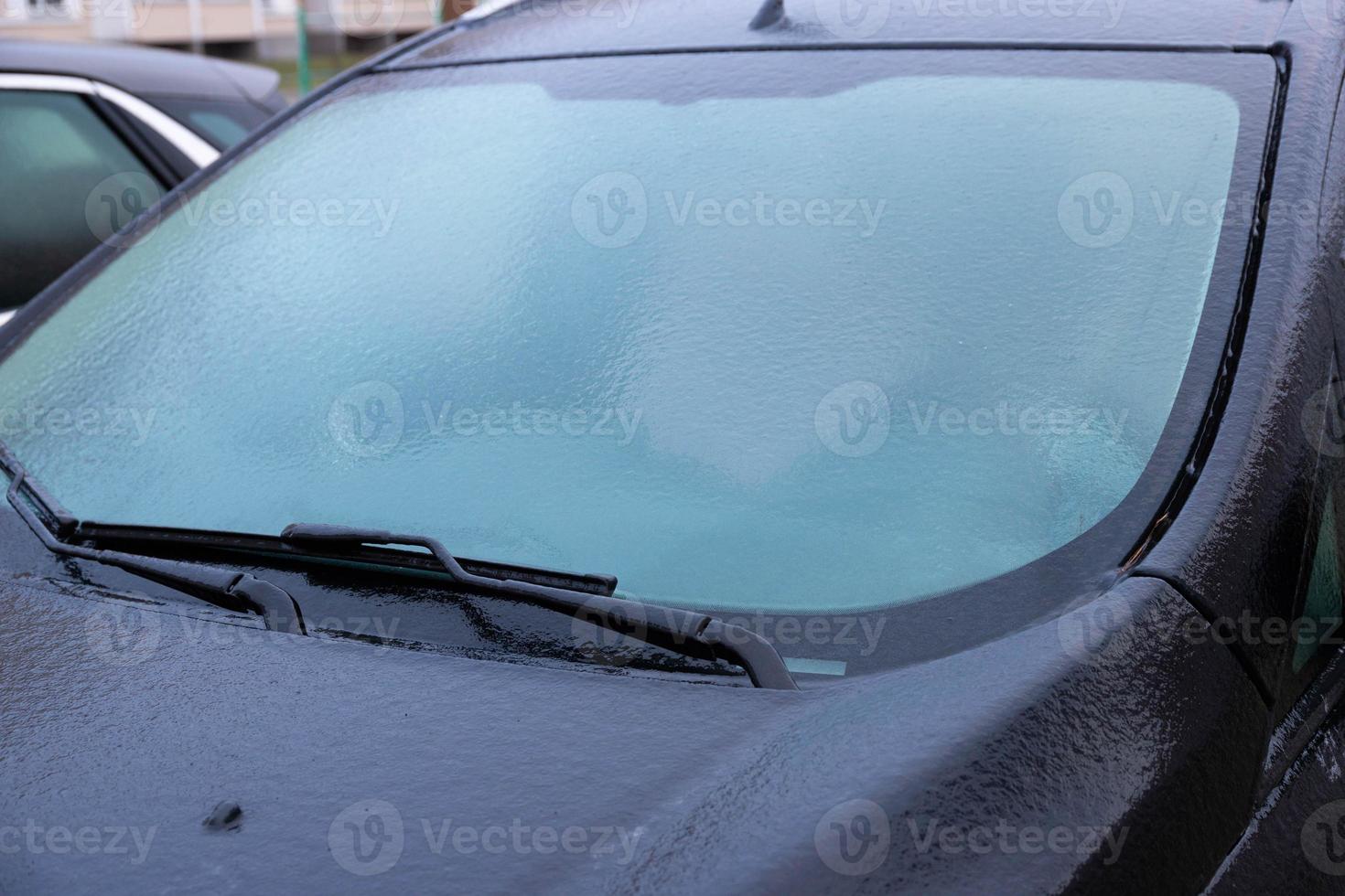 el parabrisas del coche está cubierto de hielo, a principios de invierno. foto