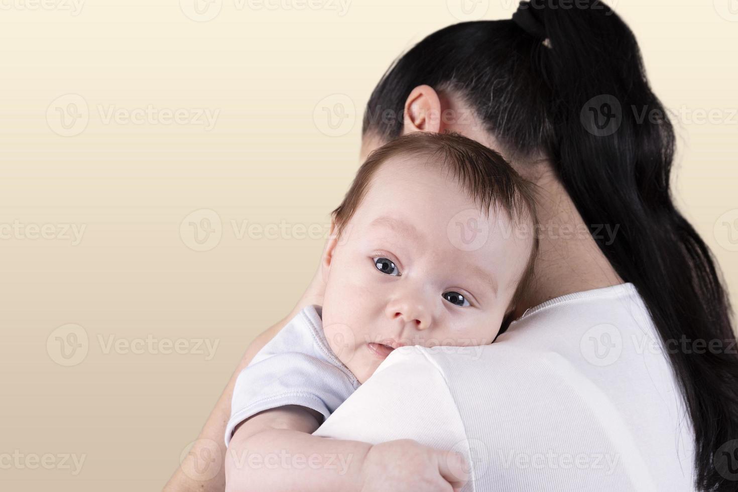 retrato de un bebé de tres meses, niño sobre el hombro de mamá. foto