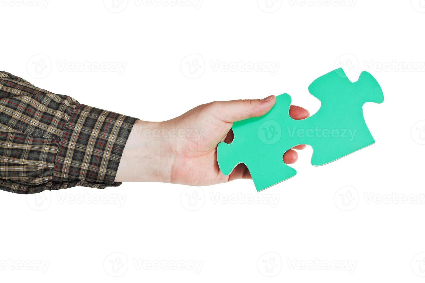 mano masculina sosteniendo una gran pieza de rompecabezas de papel verde foto