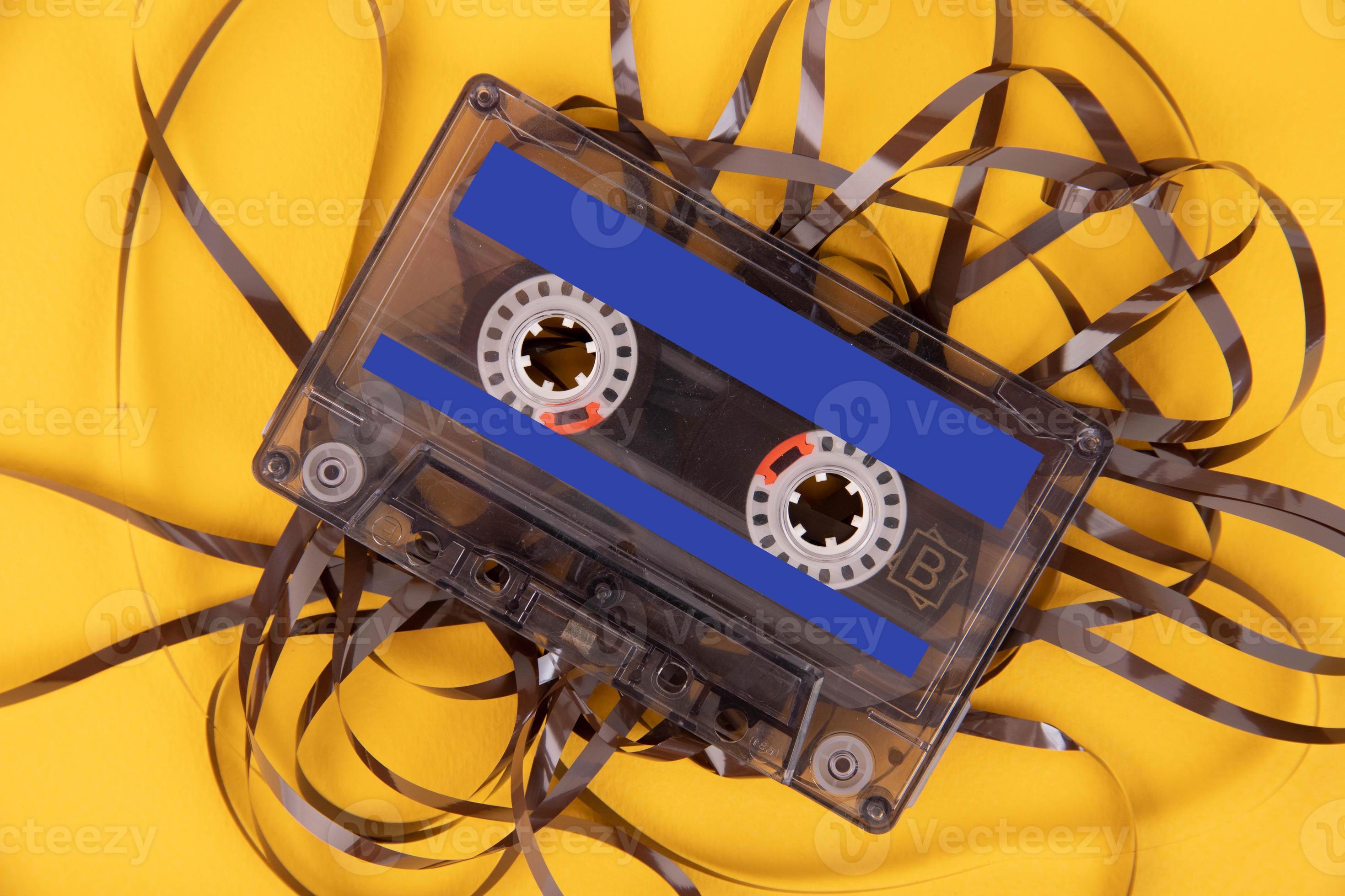 Old cassette tape with unwound tape on a yellow background. 11867542