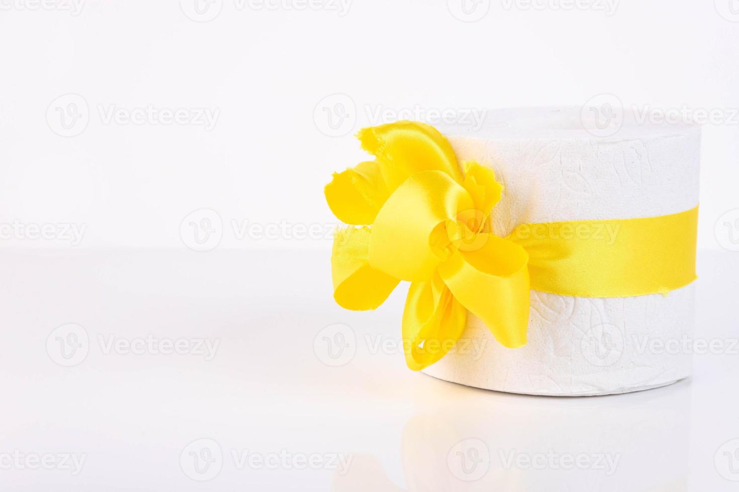 White perforated roll of soft toilet paper with a bright orange bow, as on a present. White background. Copy space photo