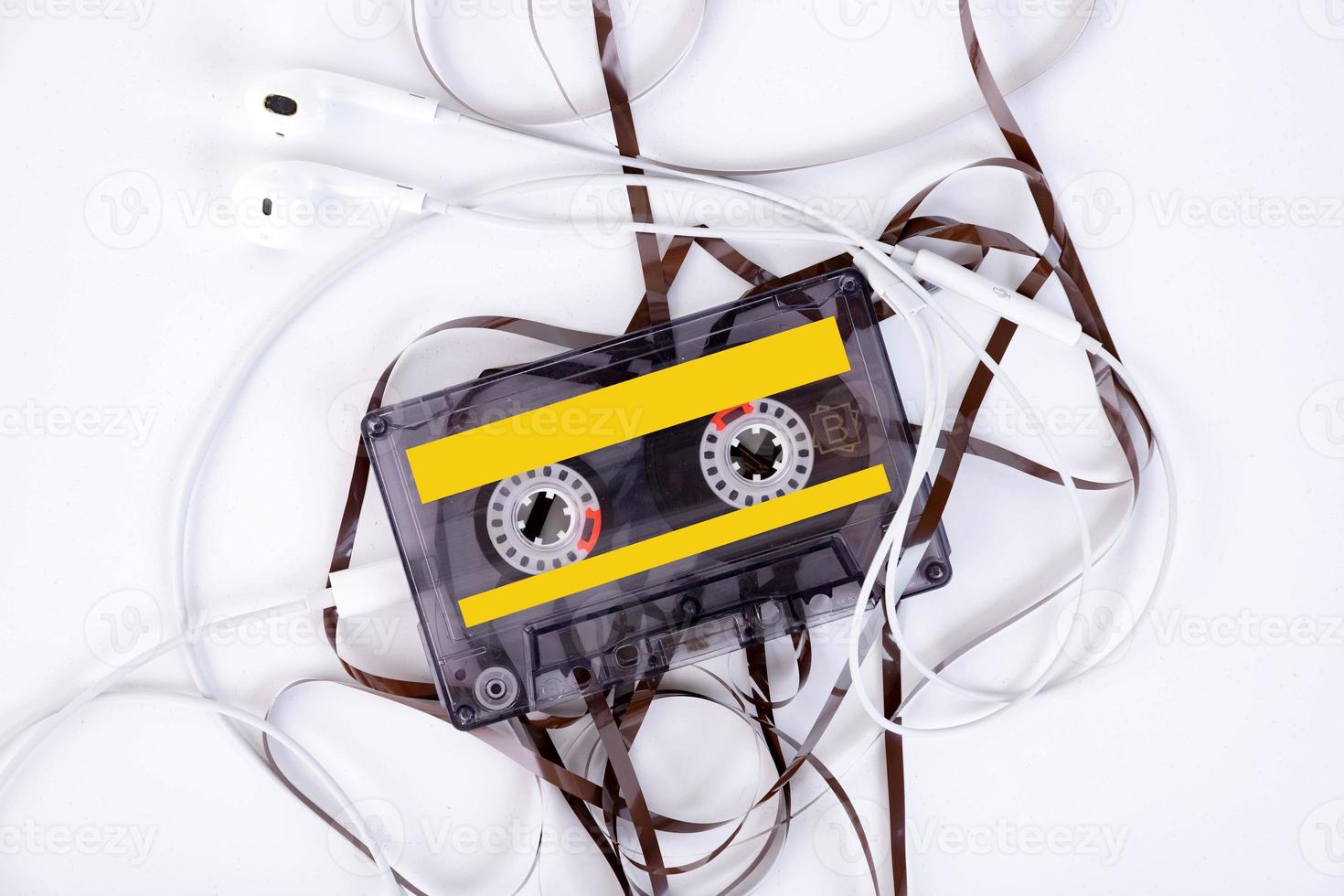 audio cassette with headphones and tangled film lying on a light background. photo