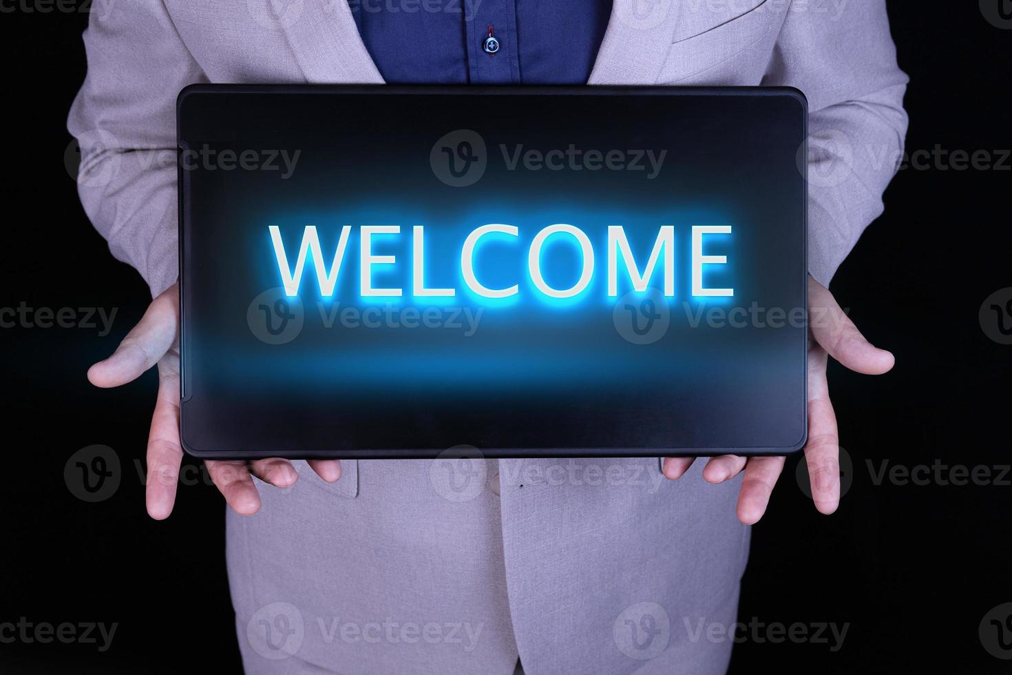 WELCOME text, word written in neon letters on a black laptop, in front of a businessman in a gray suit. photo