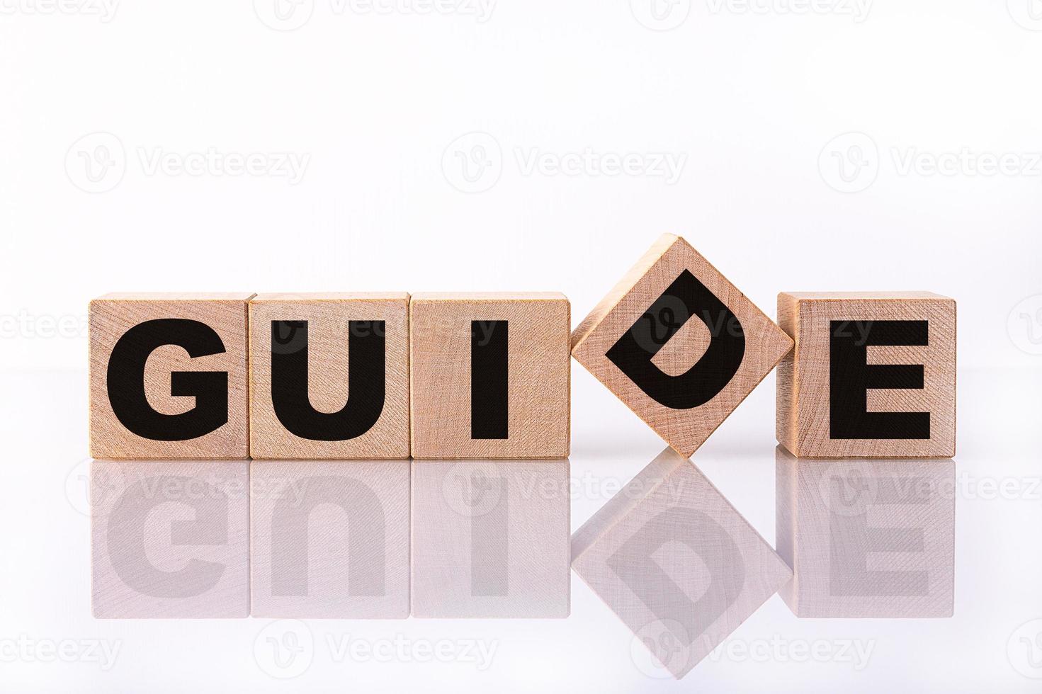 GUIDE word, text written on wooden cubes on a white background with reflection. photo