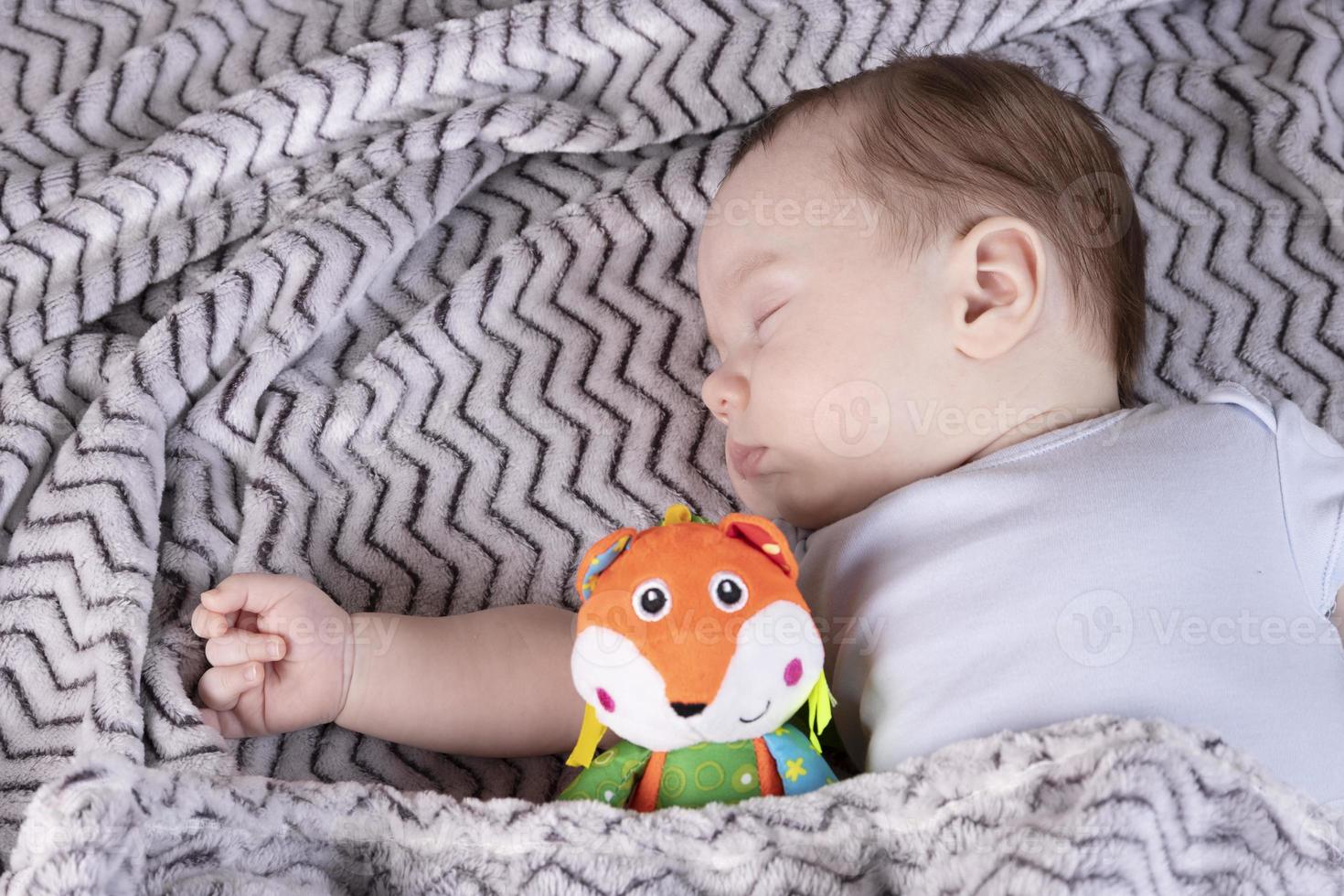 Adorable child, with a favorite toy, sleeps relaxed and sprawls on the parents' bed photo