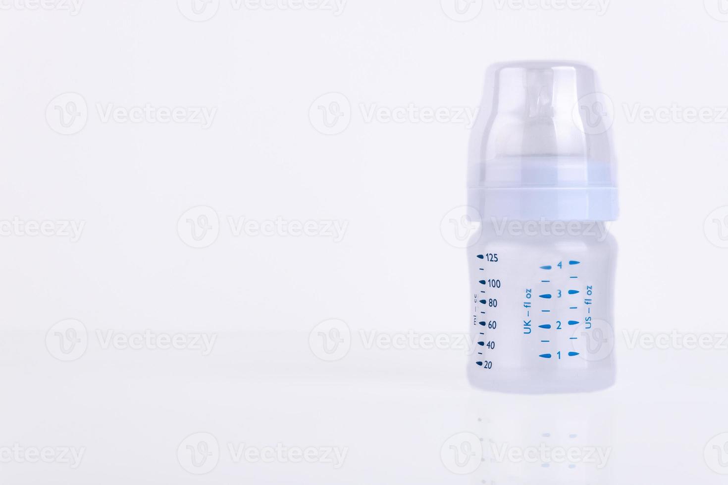 Baby bottle with pacifier and milk for feeding milk on a light background. Copy space. photo