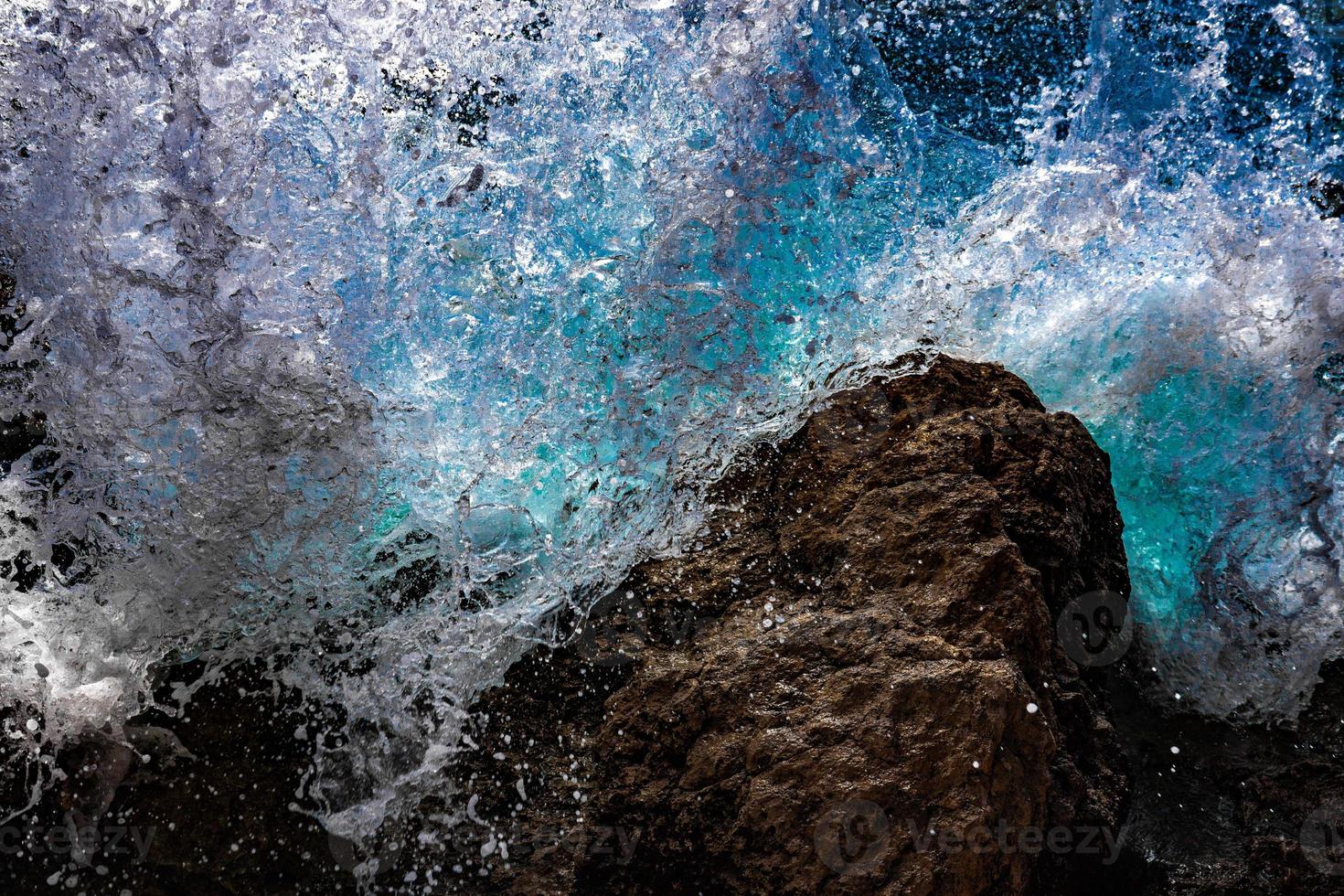 olas turquesas de agua de mar rompen y rocían gotas sobre piedras. de cerca. mar Rojo foto