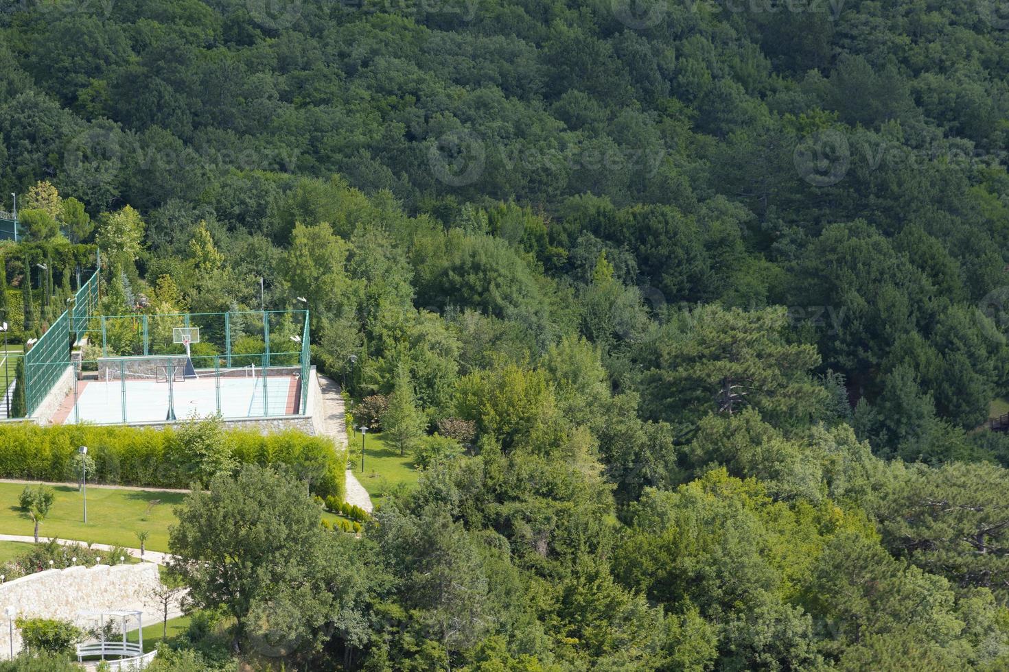 A volleyball and basketball court is located in a natural park in the mountains under the open sky. photo