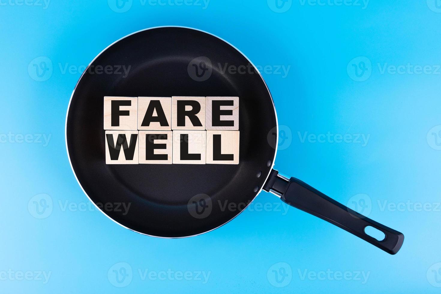 FAREWELL word, text written on wooden cubes, building blocks lying in a frying pan, and blue background. photo