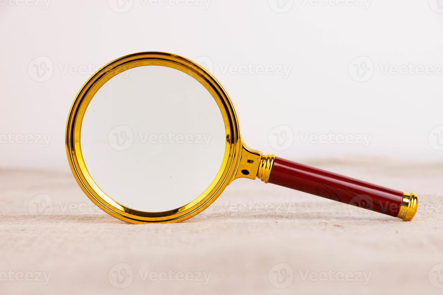 Magnifying glass of gold color on a light background and linen fabric. A copy of the space. photo