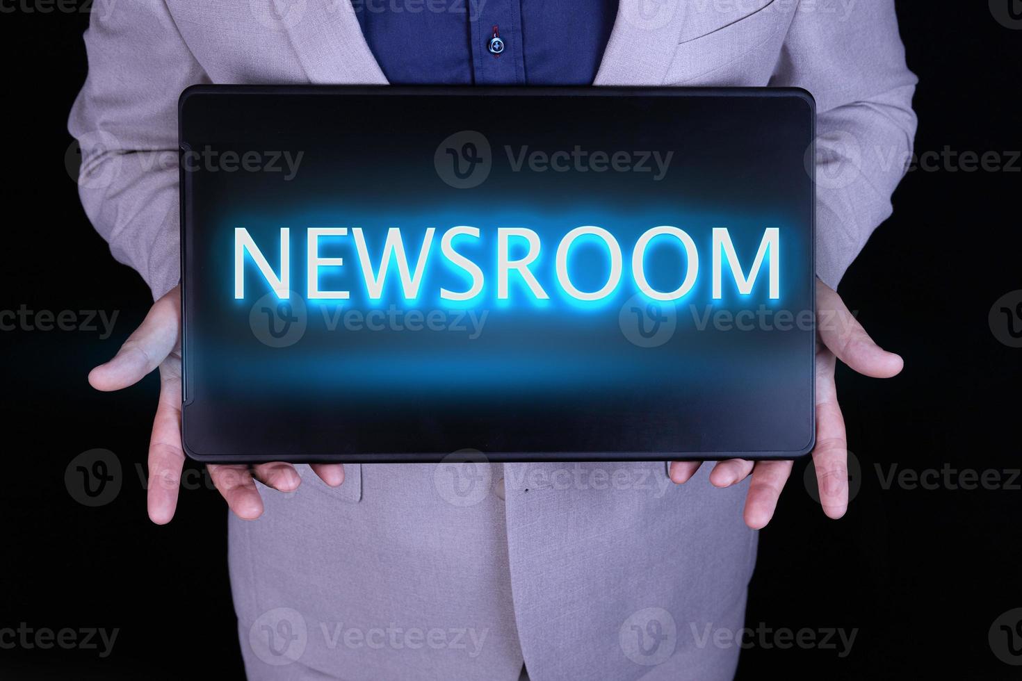 NEWSROOM text, word written in neon letters on a black laptop, in front of a businessman in a gray suit. photo