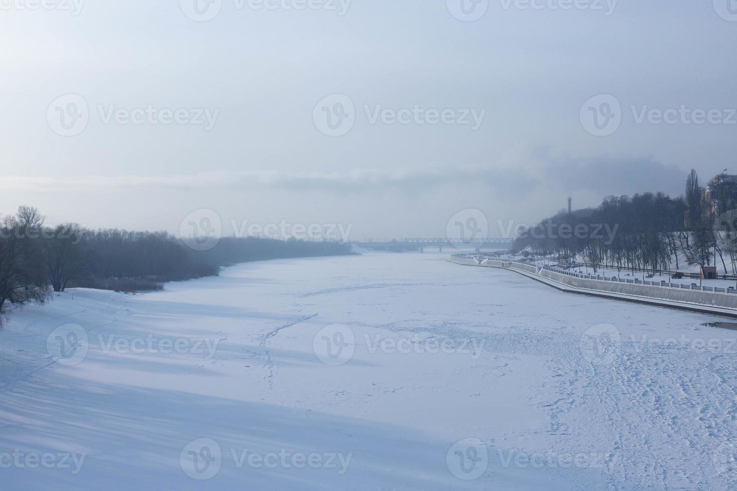 Winter landscape of ice-bound river with frost haze. photo
