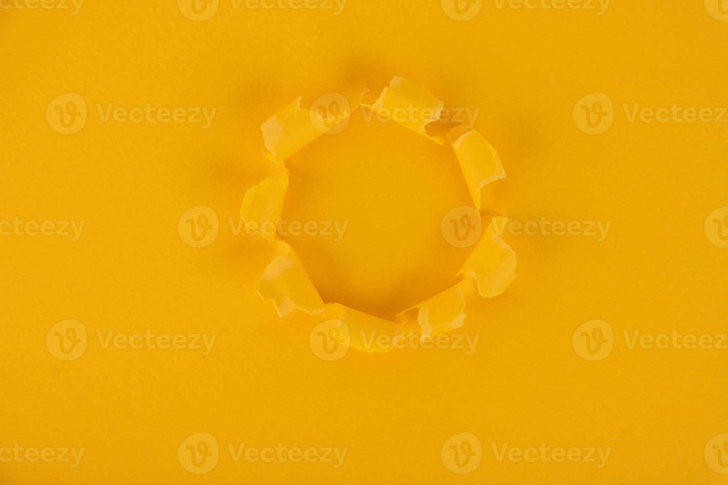 A yellow sheet of paper with a hole in the middle. Background, texture. Copy space. photo