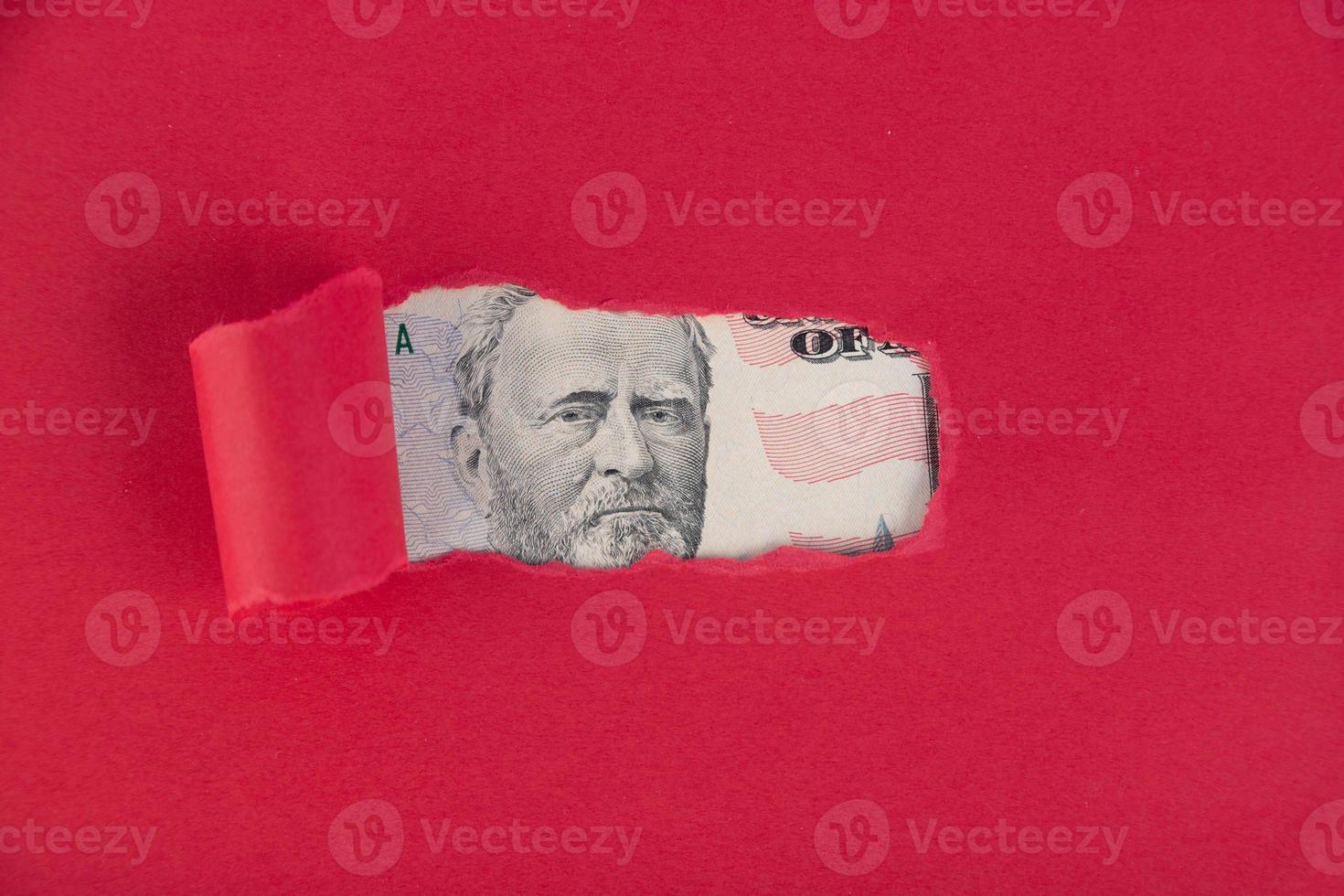 A red background, from under which a portrait of a fifty dollar bill peeps. Borrowed money concept photo