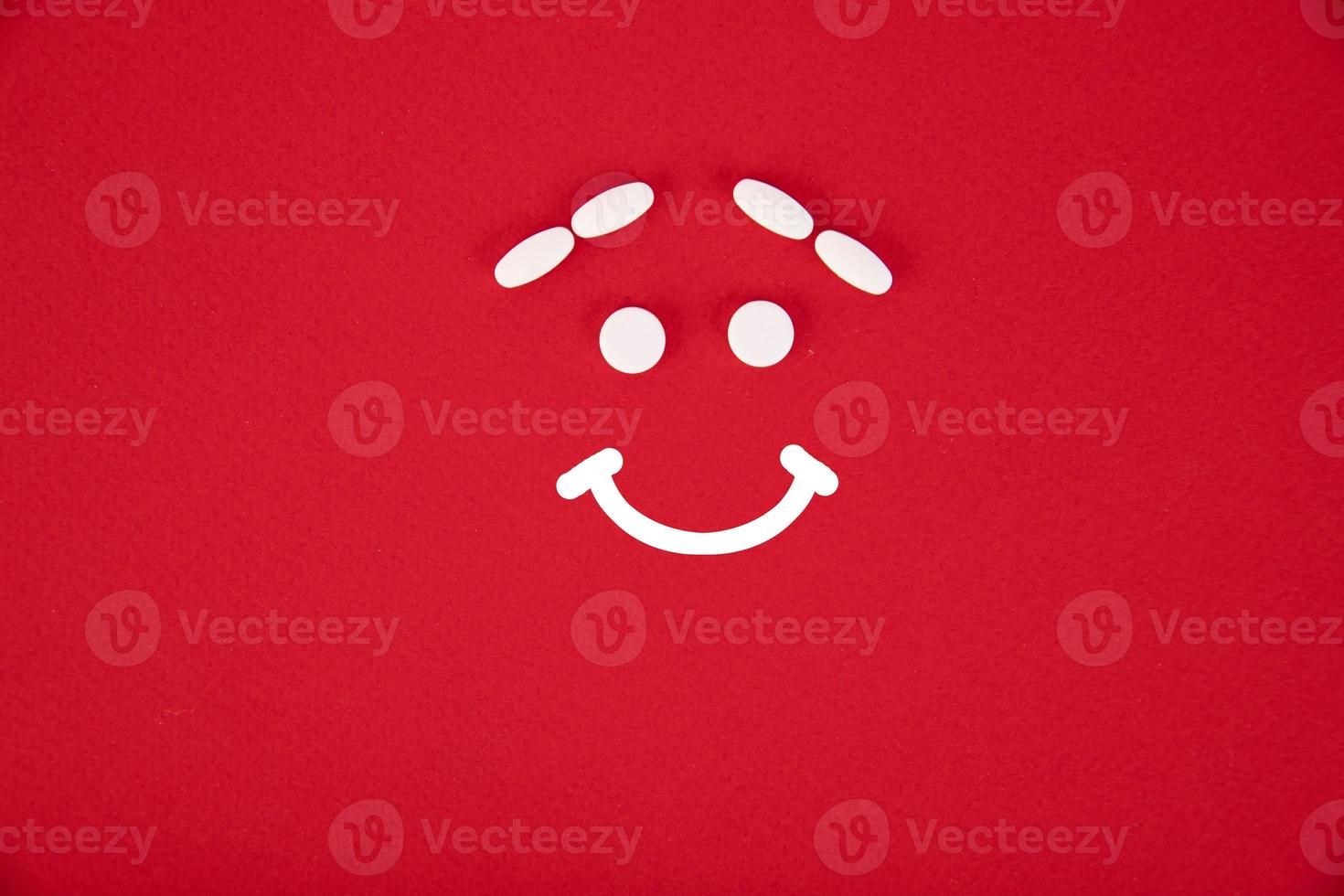 The pills are stacked in the form of a joyful emoticon on a red background. Copyspace photo